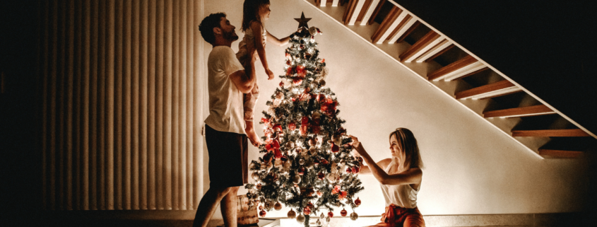 three people decorating a christmas tree